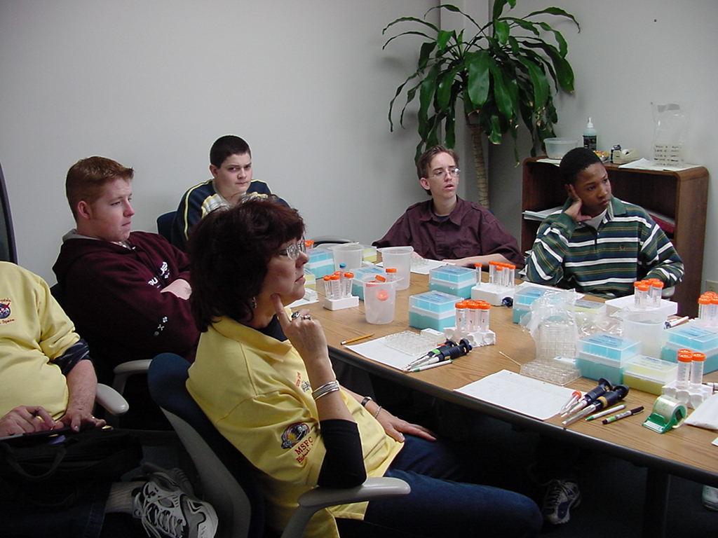 Dr. Marianne Barnes from UNF land stu8dents from Terry Parker listen intently as Anna describes the protein crystallization procedure