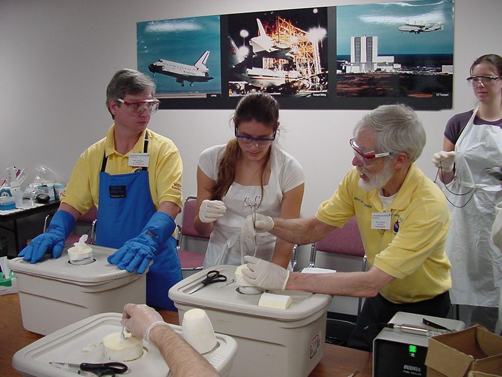 Dave Hall observes Merle Myers help a student with a flight sample